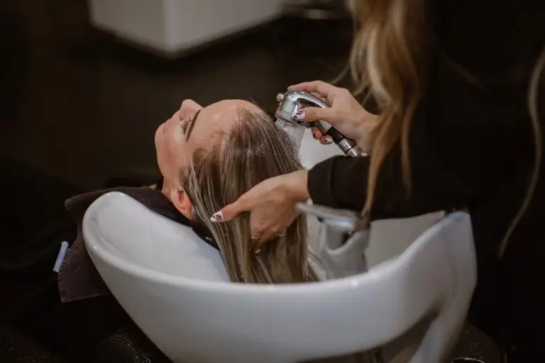 uma mulher cortando o cabelo por um cabeleireiro
